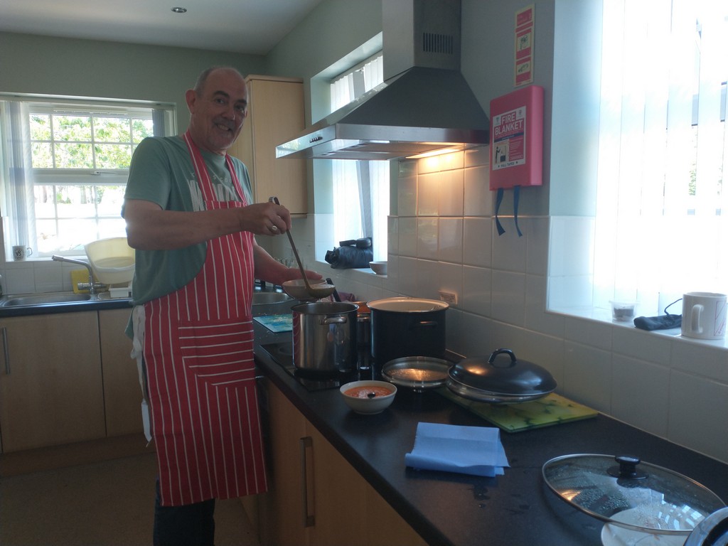volunteer in our kitchen filling a bowl of soup